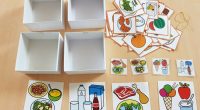 Material manipulativo tipo TEACCH para trabajar de forma lúdica la clasificación de los alimentos, distribuyéndolos en diferentes cajas de cartón, atendiendo al menú: primer plato, segundo plato, postres y bebidas.